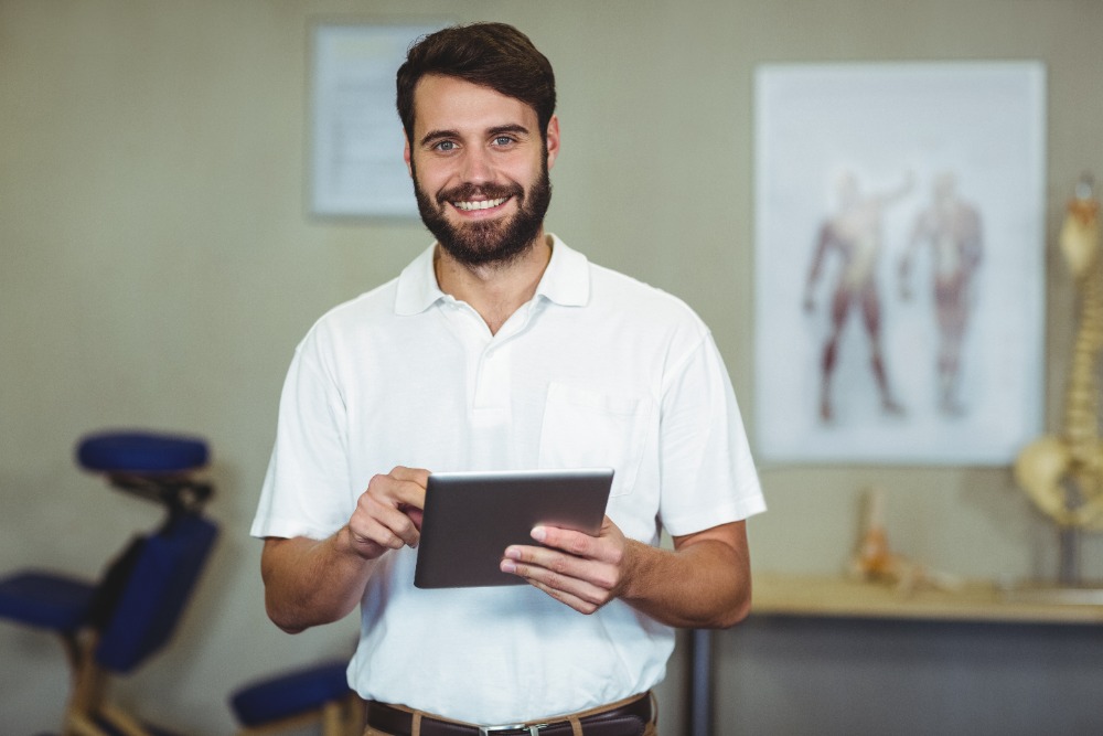 happy travel physical therapist holding a tablet